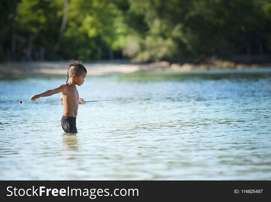 Topless Boy Wearing Black Shorts Standing On Bodies Of Water