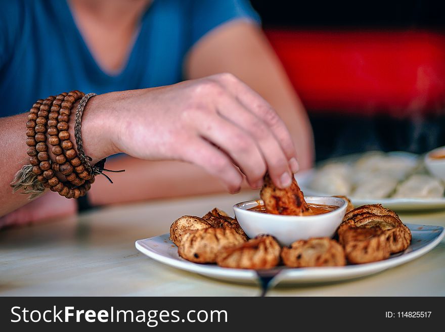 Person Holding Food and Dipping on Sauce