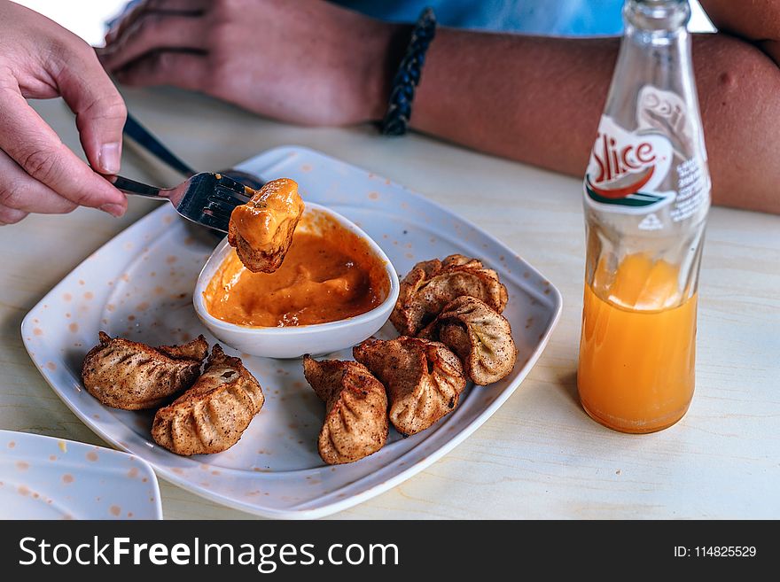 Person in Front of Table With Fried Dumplings and Soda Bottle