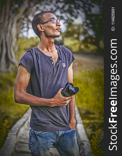 Shallow Focus Photography of Man Wearing Gray T-shirt Holding Dslr Camera Lens