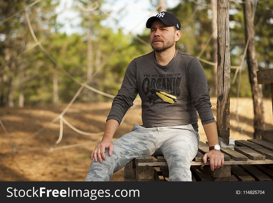 Selective Focus Photo of Man Sitting on Plank