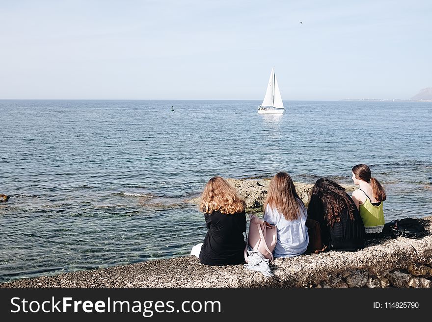 Four Women Sitting Near Sea At Daytime