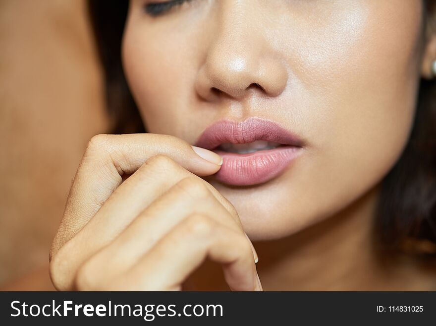 Extreme close-up of sensual young woman with plump lips, blurred background