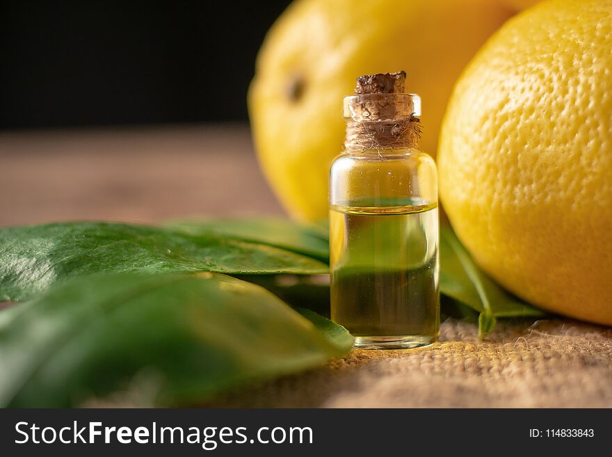 Bottles with Essential Oil of Lemon peel and leaf on wooden table