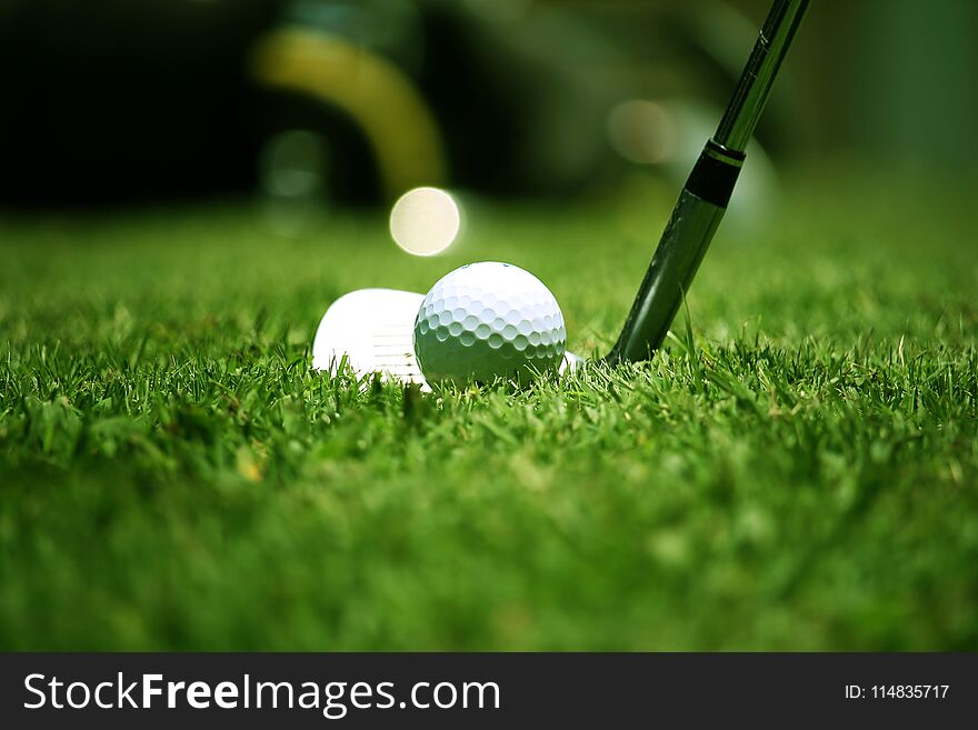 Golf club and golf ball close up in grass field with sunset. Golf ball close up in golf coures at Thailand