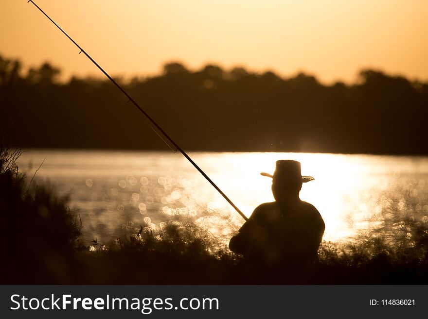 Fisherman with a fishing rod at sunset .