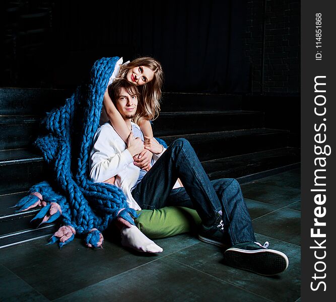 Happy beautiful young couple on the stairs with a big blue blanket. Happy beautiful young couple on the stairs with a big blue blanket