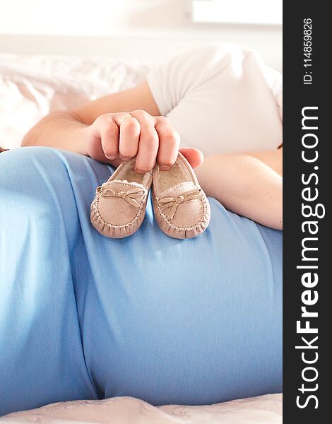 Little baby slippers on pregnancy pregnancy belly. Little baby slippers on pregnancy pregnancy belly
