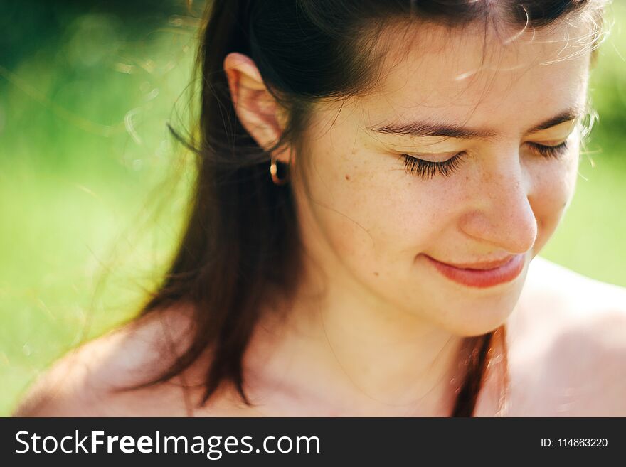 Happy cute woman smiling in sunlight on background of green nature in mountains in summer