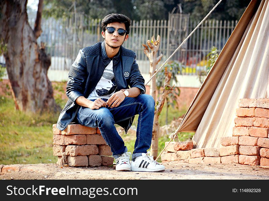 Man Wearing Sunglasses Sitting on the Concrete Bricks
