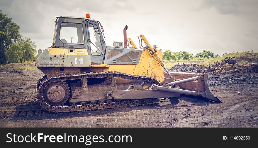 Yellow and Brown Metal Pay Loader on He Dirt
