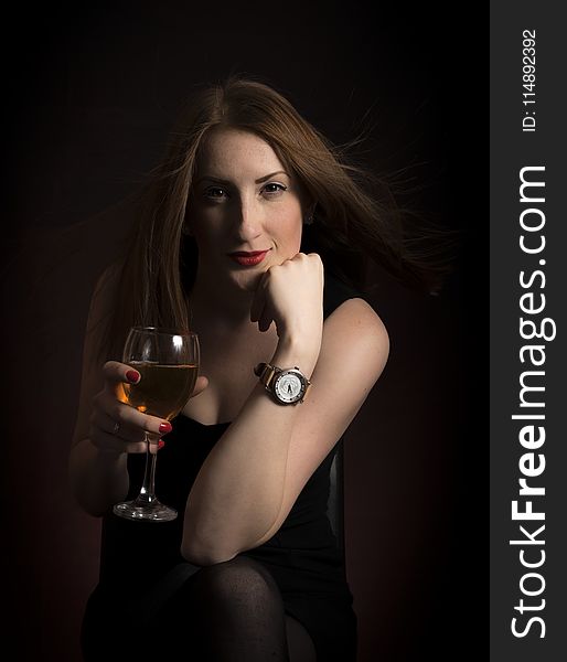 Woman Wearing Black Dress Holding Clear Wine Glass In Dark Room