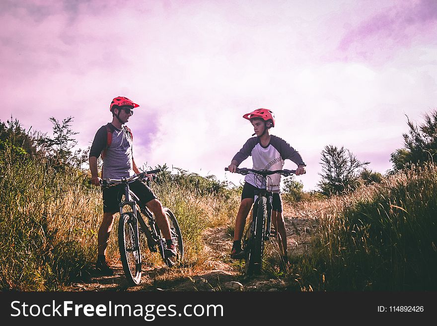 Two Man Riding Mountain Bike on Dirt Road at Daytime