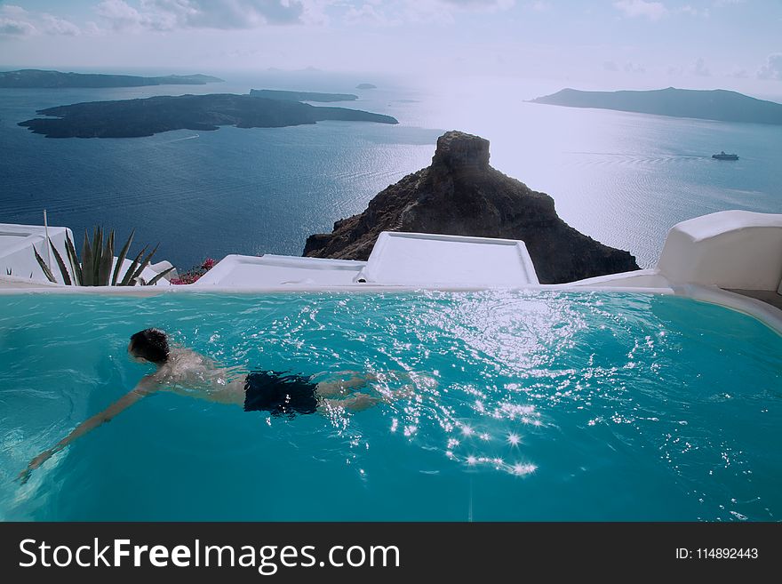 Man Wearing Black Shorts Swimming in Infinity Pool