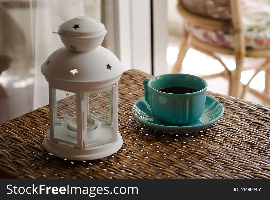 White Candle Lantern Beside of Blue Ceramic Coffee Mug on Wicker Table