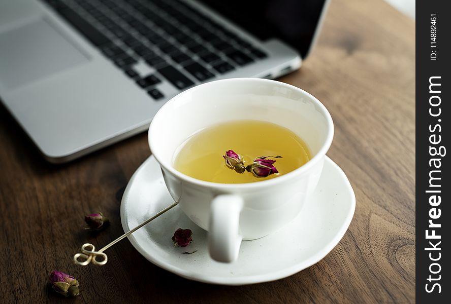 White Ceramic Teacup on Saucer Beside Laptop Computer