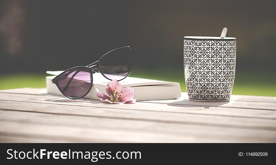 Photo of Black Sunglasses Beside Ceramic Mug