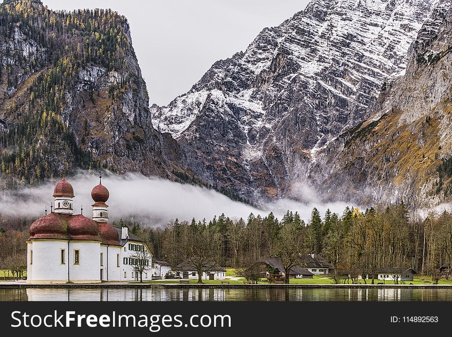 White And Brown Mosque Beside Body Of Water Near Rocky Mountain