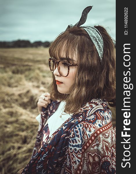 Selective Focus Shot Of Woman In White And Brown Floral Standing On Grass Field