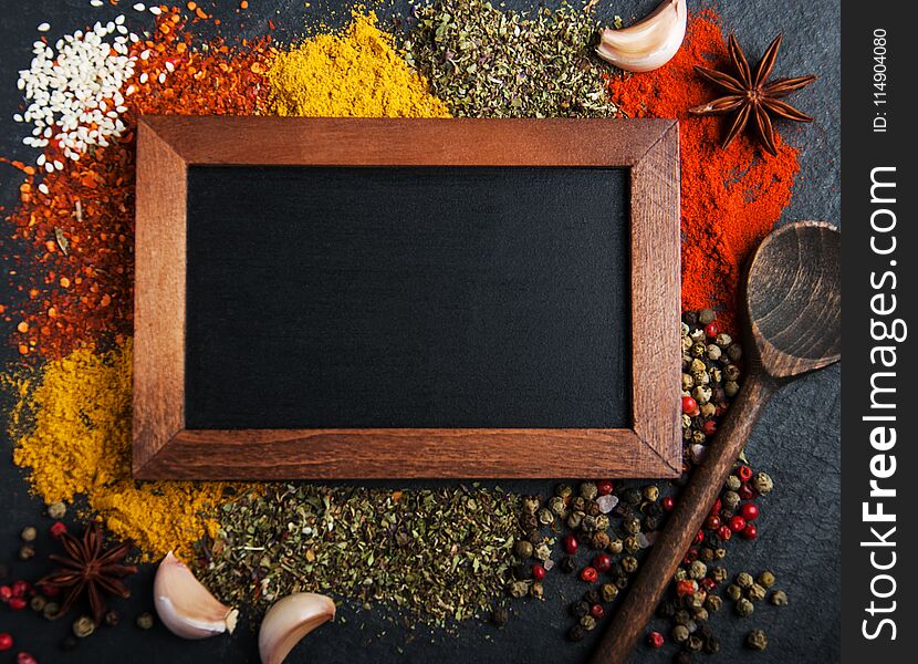 Different kind of spices and blackboard on a black stone background