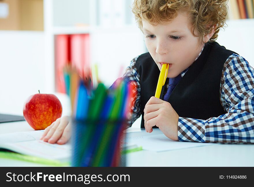 Curly Caucasian Boy Thought About The Task And Took A Pen In His Mouth During The Lesson At School. Education, Childhood