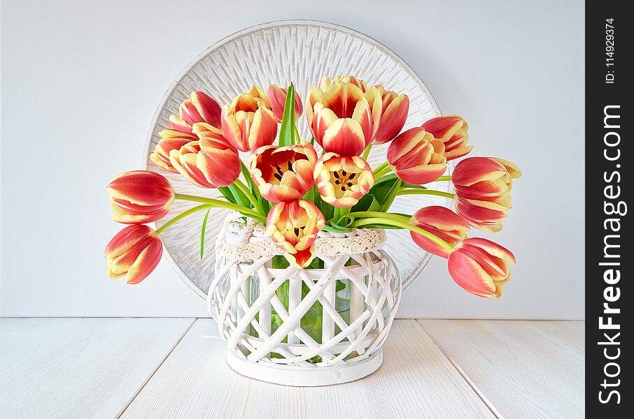 Bunch of red-yellow tulips on white wooden background, central composition