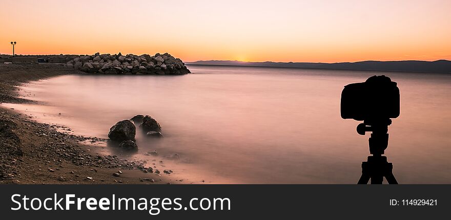 Camera on tripod with sunset over the sea in background / Podgora, Croatia