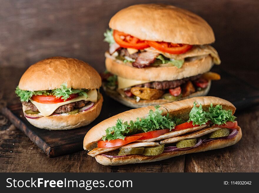 Chicken sandwich and two different kinds of hamburgers on wooden table