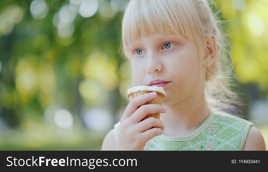 Thoughtful girl 6 years old is eating ice cream in the park. Holiday in summer and vacations