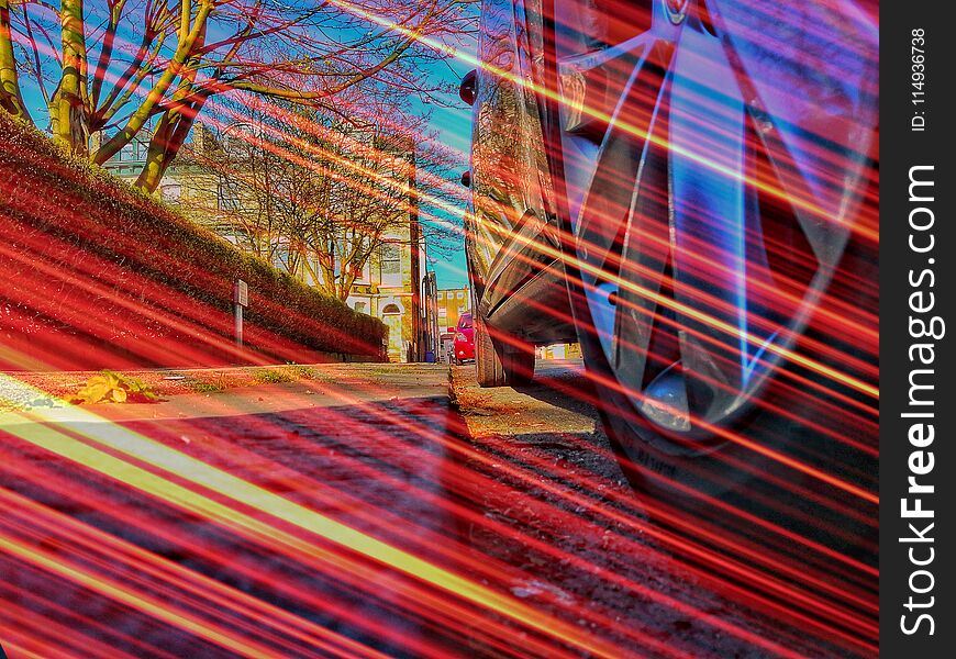 Low angle street view of car wheel taken on a sunny day and layered with a long exposure light flare. Low angle street view of car wheel taken on a sunny day and layered with a long exposure light flare.