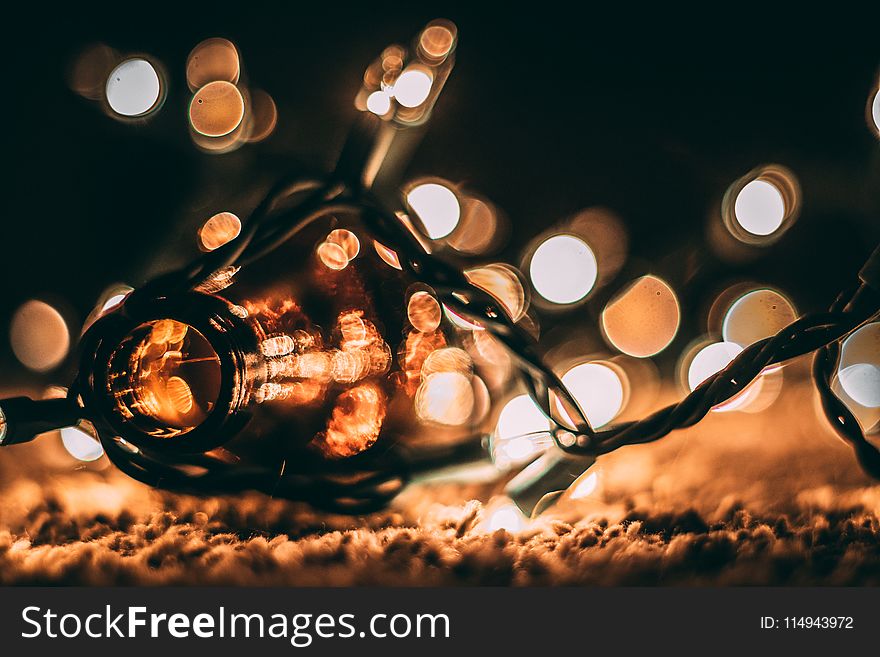 Low-light Photo of Amber Glass Bottle With String Lights and Beige Bokeh