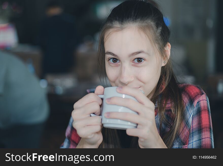 Beautiful caucasian woman holding a cup of coffee in her hand on blurred background