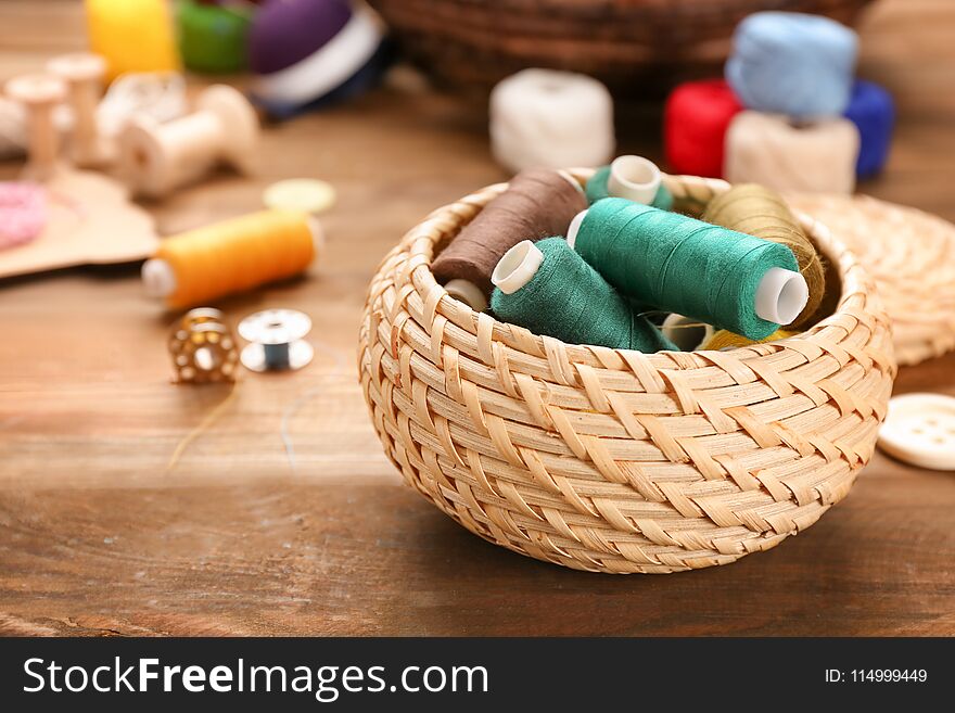 Small box with set of color sewing threads on wooden background