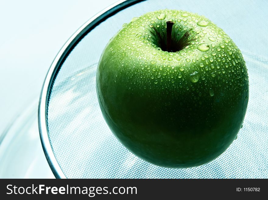 Wet green apple in brilliant drops of water
