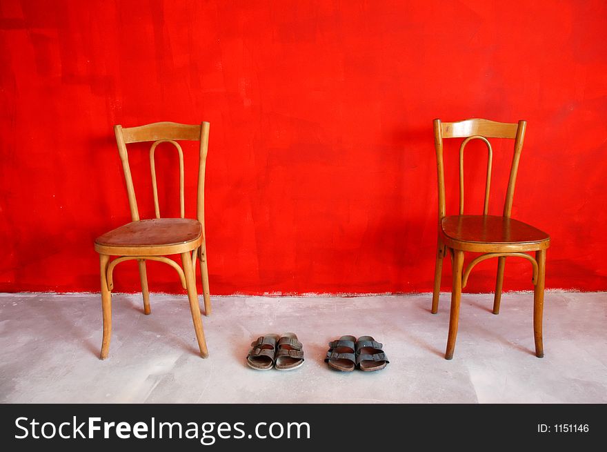 Two chairs and slippers before red wall