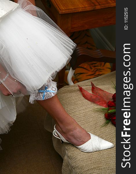 Bride putting garter on her leg. Bride putting garter on her leg