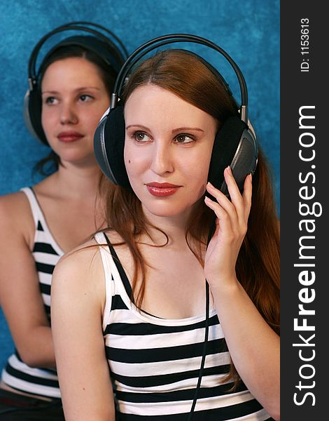 Two beautiful young woman wearing headphones and listen to music. Two beautiful young woman wearing headphones and listen to music.