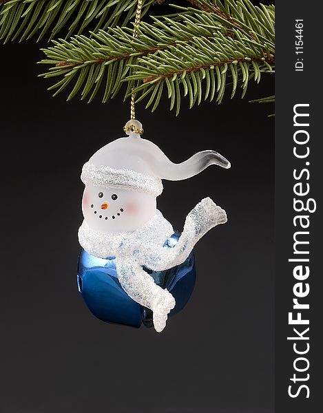 Blue snow bell Christmas tree ornament hanging on branch.