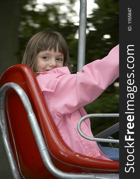 Young girl on the playground-lift in the red seat