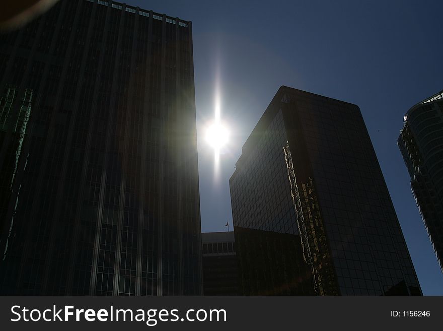 Silouette of downtown office towers with sun gleaming behind. Silouette of downtown office towers with sun gleaming behind.