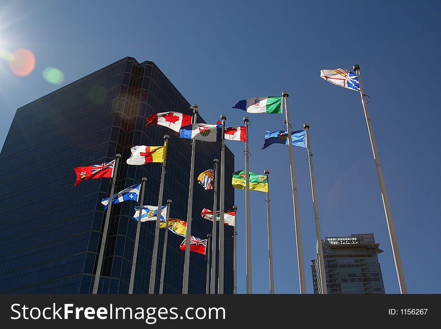 Flags with vibrant colors flying with blue sky, buildings and lense flare. Flags with vibrant colors flying with blue sky, buildings and lense flare.