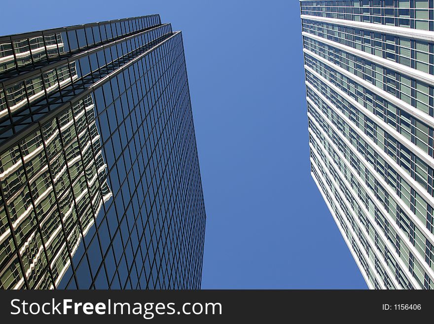 Looking up at two corporate downtown office buildings toward the blue sky. Perfect for corporate brochure. Looking up at two corporate downtown office buildings toward the blue sky. Perfect for corporate brochure.