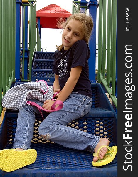Young school girl sitting on playground equipment steps at recess. Young school girl sitting on playground equipment steps at recess