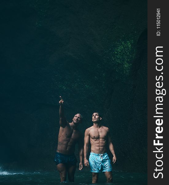 Two Men in Blue Shorts on Body of Water