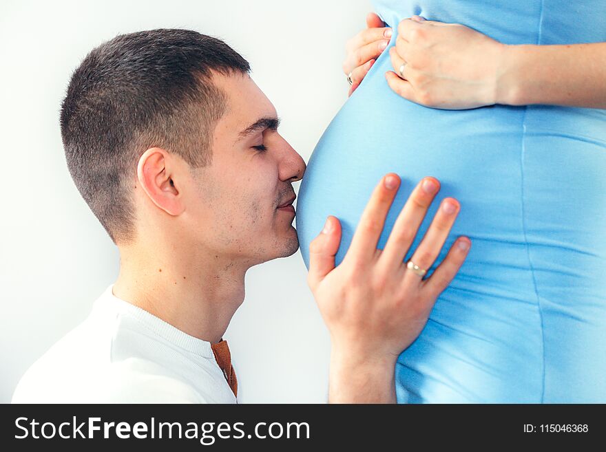 Close up of a men kissing the belly of his lovely pregnant wife standing in the bedroom. Close up of a men kissing the belly of his lovely pregnant wife standing in the bedroom