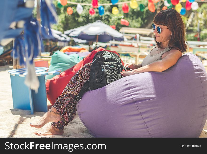 Woman Wearing Gray Tank Top Sitting on Purple Bean Bag