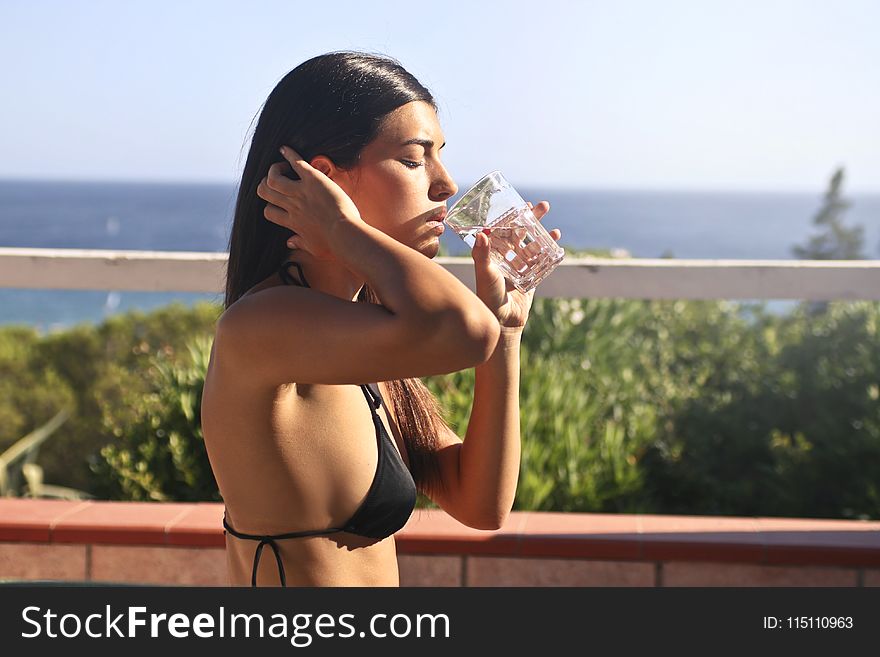 Photography of a Woman Wearing Black Bikini Drinking Water