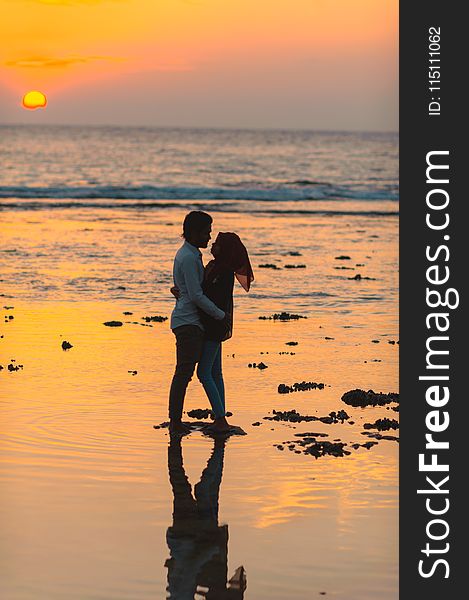 Man and Woman Hugging by the Seashore during Sunset