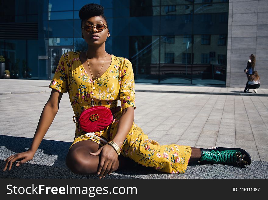 Woman In Yellow Floral Jumpsuit Sitting On Concrete Floor