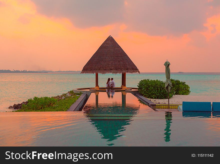 Couple Under Hut Beside Sea and Infinity Pool